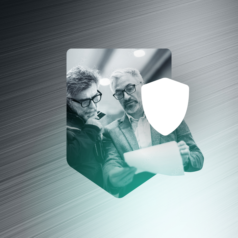 Two professionals reviewing documents inside a shield icon representing financial security.