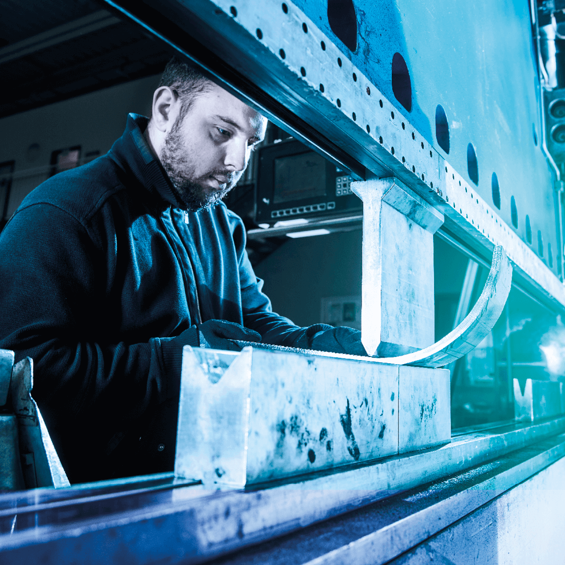 Ein Arbeiter bedient eine große industrielle Kantbank zum Biegen von Metallteilen in einer Werkstatt.