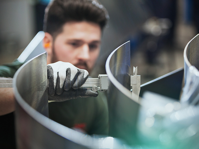 Craftsman measuring curved metal parts with caliper