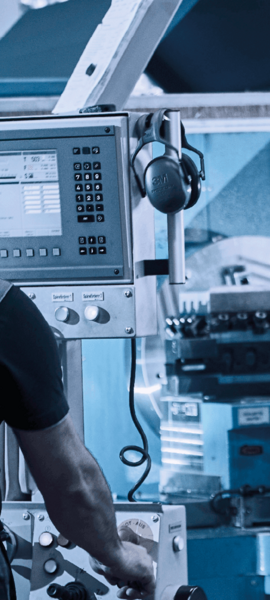 Operator in workwear operating a modern CNC lathe in a workshop.