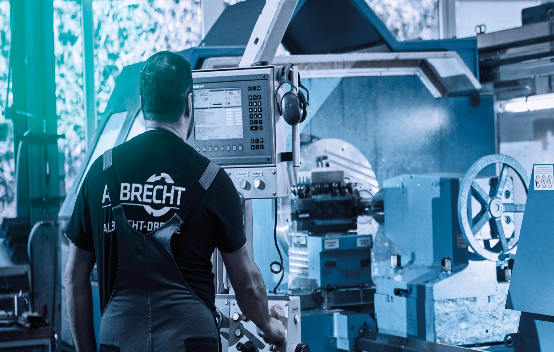 Operator in workwear operating a modern CNC lathe in a workshop.
