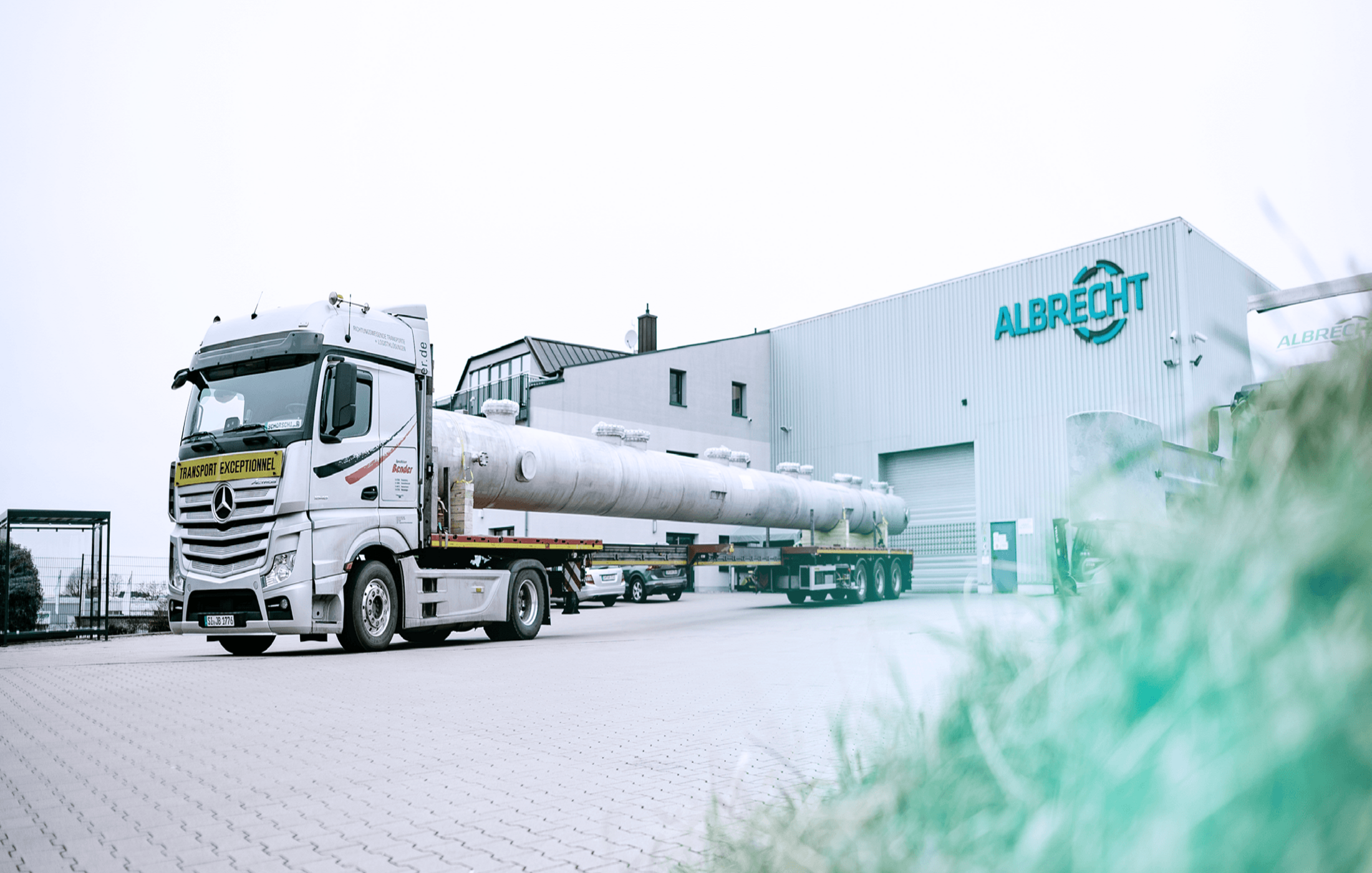 Truck with a long industrial pipe in front of the Albrecht building