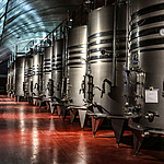 Große Edelstahltanks in einer Weinkellerei mit rotem Boden