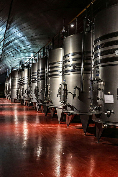 Große Edelstahltanks in einer Weinkellerei mit rotem Boden