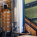 Großer Edelstahltank und Holztank in einer modernen Brauerei.