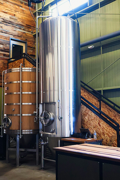 Großer Edelstahltank und Holztank in einer modernen Brauerei.